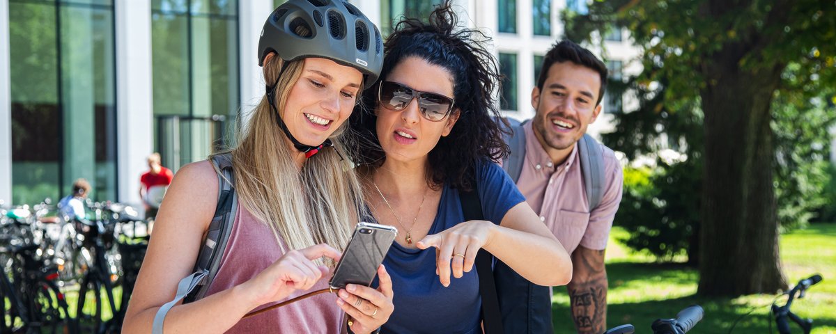 Radfahrerinnen schauen gemeinsam auf ein Smartphone.